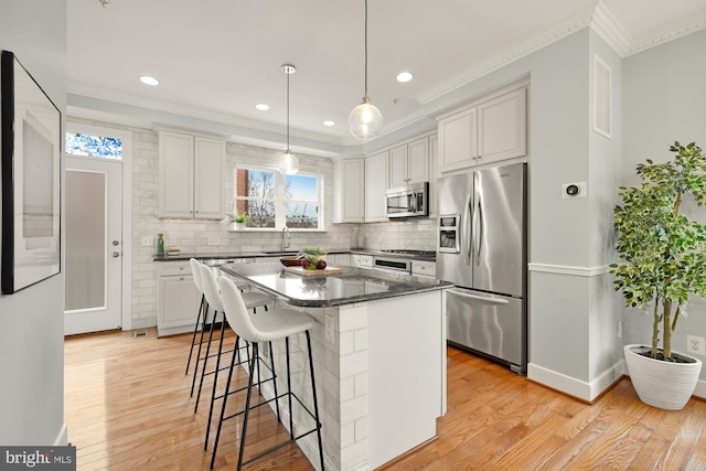 kitchen with a breakfast bar, light wood-type flooring, stainless steel appliances, and a sink