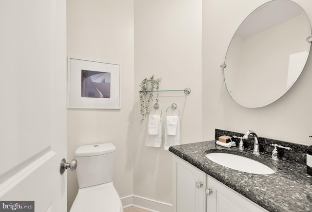 half bath with toilet, baseboards, and vanity