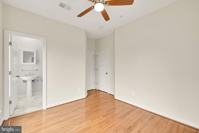 unfurnished bedroom with light wood-type flooring, ensuite bath, visible vents, and baseboards