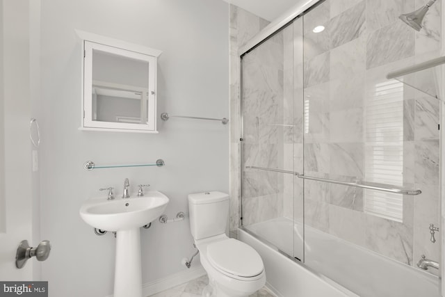 full bathroom featuring toilet, shower / bath combination with glass door, a sink, baseboards, and marble finish floor