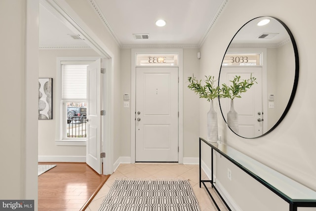 entrance foyer featuring visible vents, crown molding, light wood finished floors, and baseboards