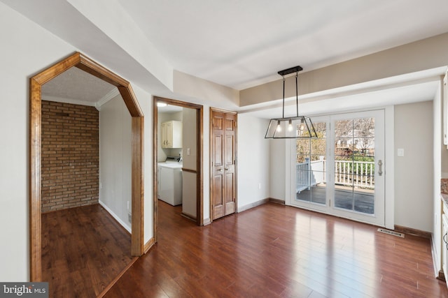 unfurnished dining area featuring visible vents, dark wood-type flooring, brick wall, washer / dryer, and baseboards