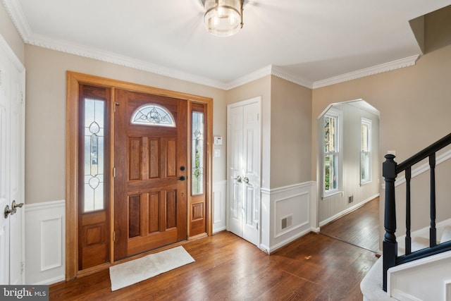 foyer featuring a wealth of natural light, a wainscoted wall, stairway, and wood finished floors