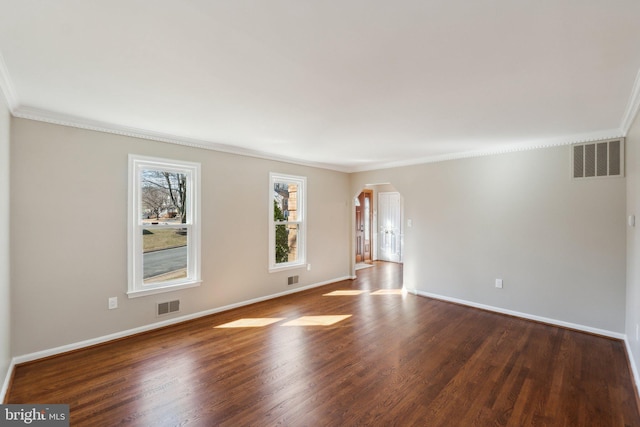 empty room with arched walkways, wood finished floors, visible vents, baseboards, and ornamental molding