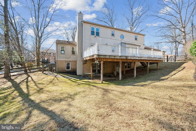 rear view of property featuring a wooden deck, a chimney, fence, and a lawn