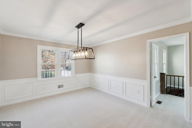 unfurnished dining area with carpet, a wainscoted wall, visible vents, and crown molding