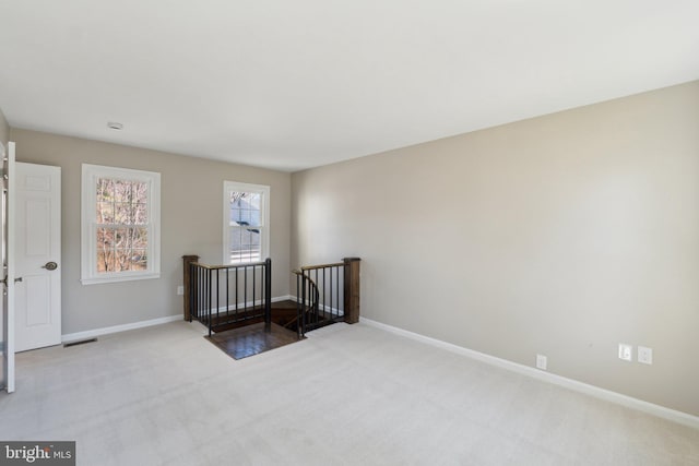 empty room with light carpet, visible vents, and baseboards