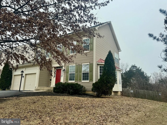 view of front of property with an attached garage, fence, and aphalt driveway