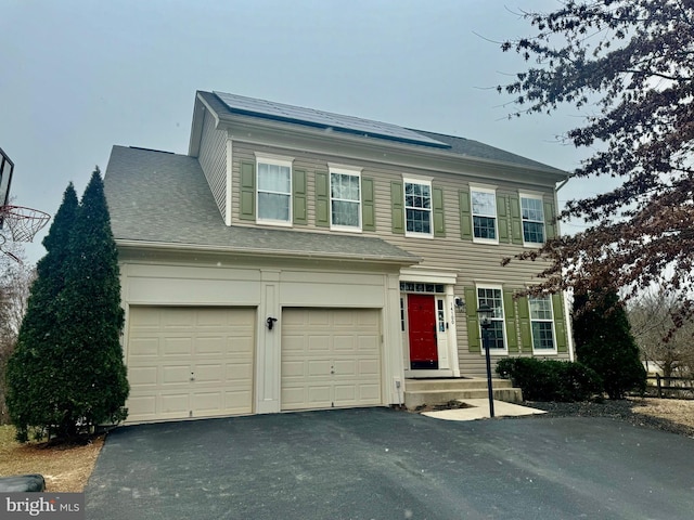 view of front facade with a shingled roof and driveway