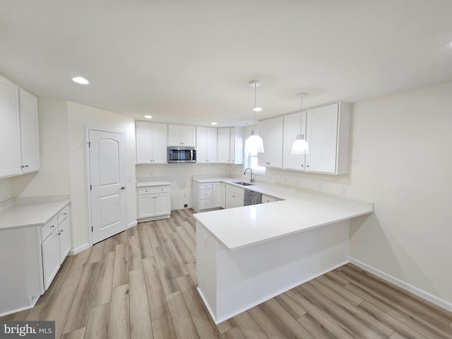 kitchen with white cabinets, appliances with stainless steel finishes, decorative light fixtures, and kitchen peninsula