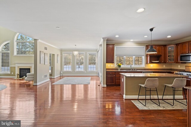 kitchen with glass insert cabinets, a center island, hanging light fixtures, stainless steel appliances, and a kitchen bar
