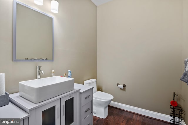 bathroom with vanity, wood finished floors, toilet, and baseboards