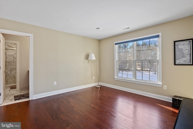 unfurnished room featuring dark wood-style floors, visible vents, and baseboards
