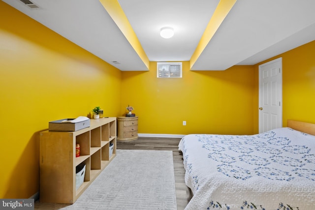 bedroom featuring visible vents, baseboards, and wood finished floors