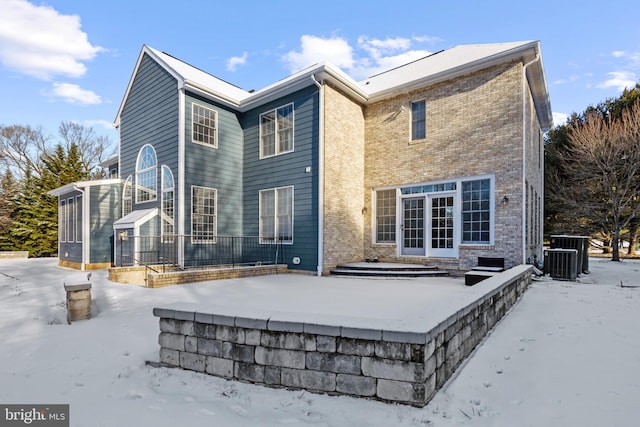 back of property with brick siding and central AC unit