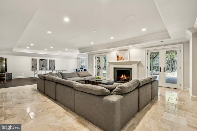 living area with ornamental molding, french doors, a tray ceiling, and baseboards