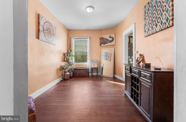 corridor featuring dark wood-style flooring and baseboards