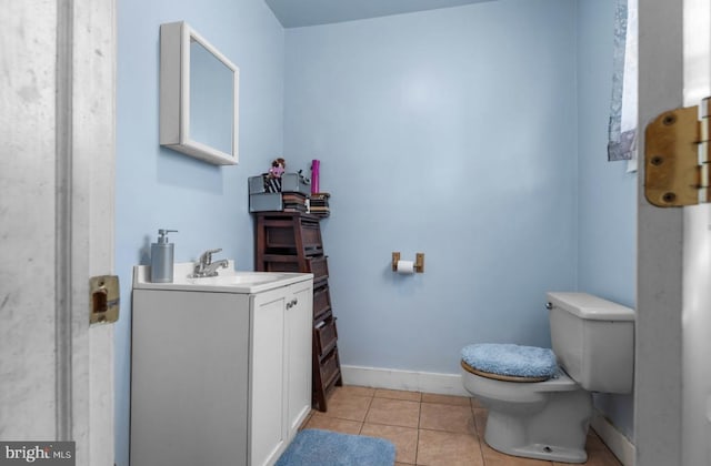 half bath featuring toilet, tile patterned flooring, vanity, and baseboards