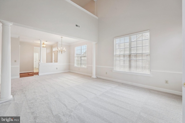 unfurnished living room featuring decorative columns, a notable chandelier, and light colored carpet