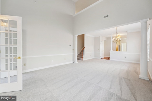 unfurnished room with carpet floors, visible vents, stairway, and ornate columns