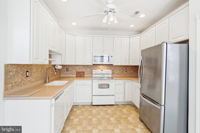 kitchen featuring white appliances, white cabinetry, light countertops, and a sink