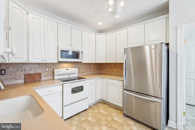 kitchen with white appliances, white cabinetry, and light countertops