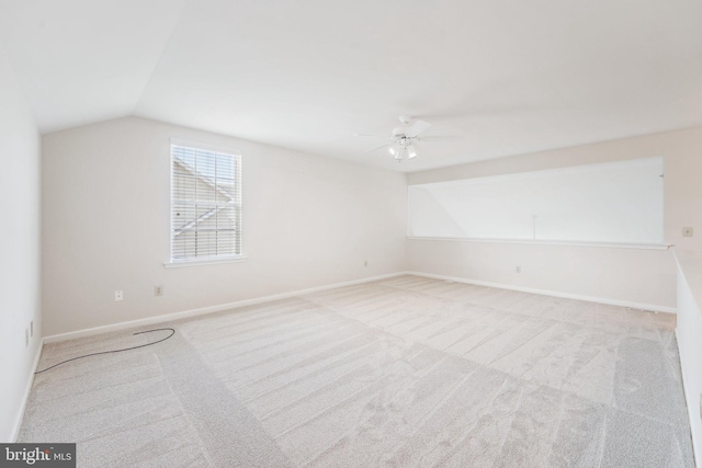 spare room featuring vaulted ceiling, baseboards, a ceiling fan, and light colored carpet