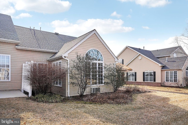 exterior space with roof with shingles and a front yard