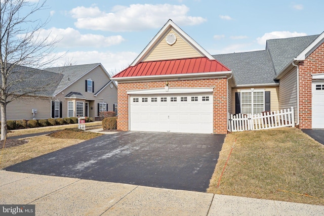 traditional-style home with brick siding, an attached garage, a standing seam roof, fence, and driveway