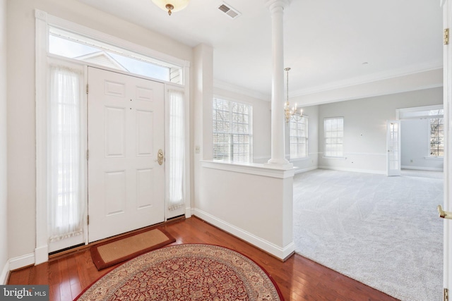 foyer entrance featuring visible vents, decorative columns, baseboards, and wood finished floors