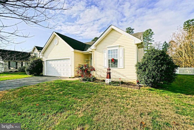 ranch-style house featuring an attached garage, a front lawn, and aphalt driveway