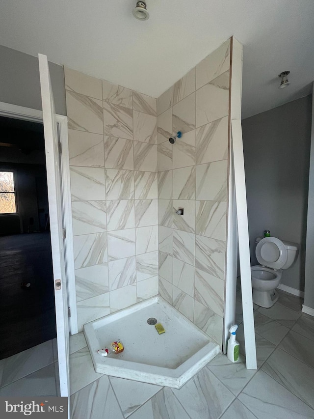 bathroom with tiled shower and toilet