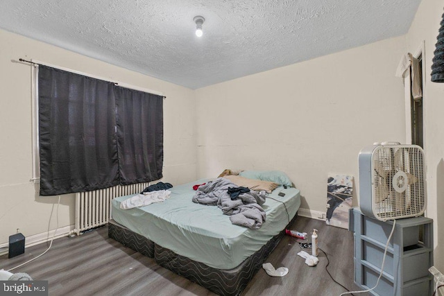 bedroom with a textured ceiling, radiator, and dark hardwood / wood-style floors