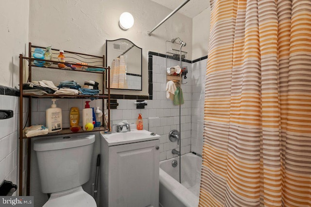 full bathroom featuring toilet, tile walls, tiled shower / bath combo, and vanity