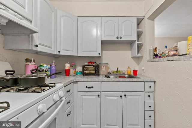 kitchen with white gas range, sink, and white cabinets