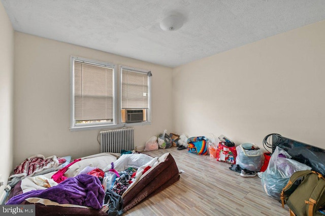 bedroom featuring radiator, cooling unit, a textured ceiling, and hardwood / wood-style floors