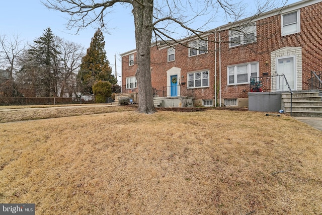 view of property featuring brick siding and a front lawn