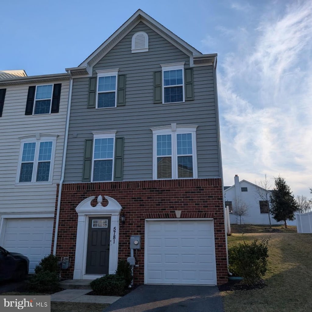 multi unit property featuring aphalt driveway, brick siding, and a garage