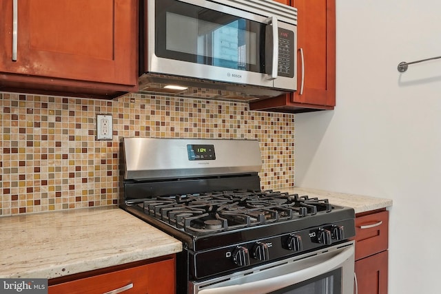 kitchen featuring brown cabinetry, light stone counters, stainless steel appliances, and decorative backsplash