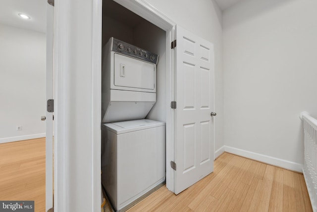 laundry area with laundry area, baseboards, light wood-style flooring, stacked washing maching and dryer, and recessed lighting