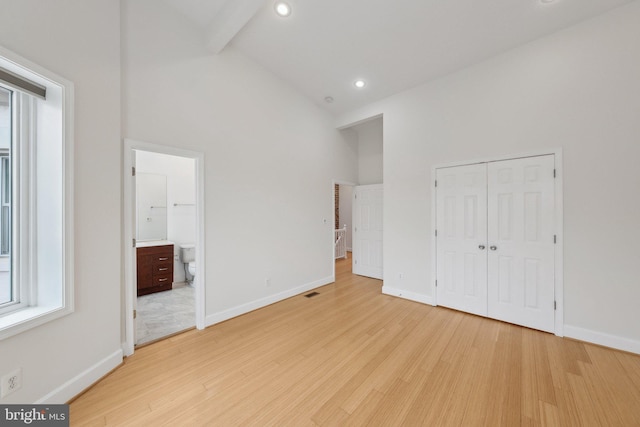 unfurnished bedroom featuring high vaulted ceiling, light wood-style floors, and baseboards