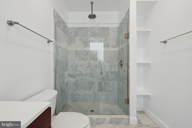 bathroom with vanity, a shower stall, toilet, and baseboards