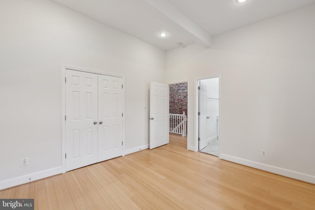 unfurnished bedroom with beam ceiling, baseboards, wood finished floors, and recessed lighting