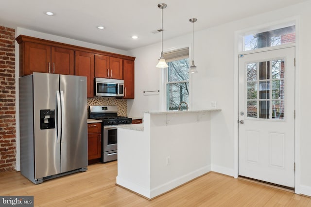 kitchen featuring stainless steel appliances, a peninsula, light wood-style flooring, and decorative backsplash