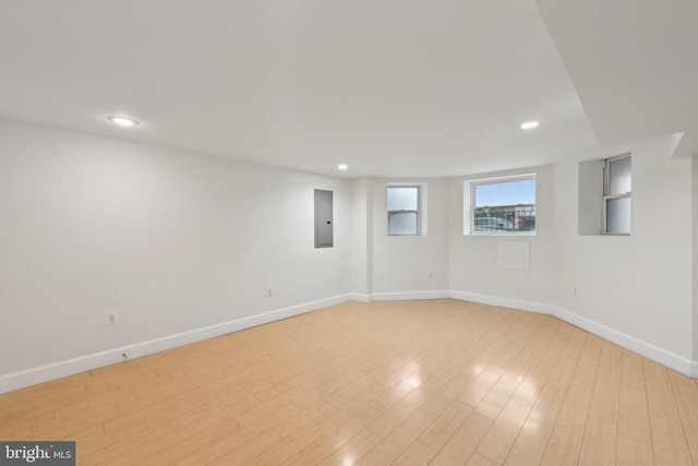 below grade area with light wood-style flooring, electric panel, baseboards, and recessed lighting