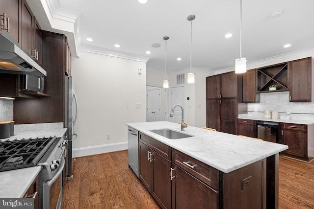 kitchen with a center island with sink, sink, pendant lighting, and appliances with stainless steel finishes