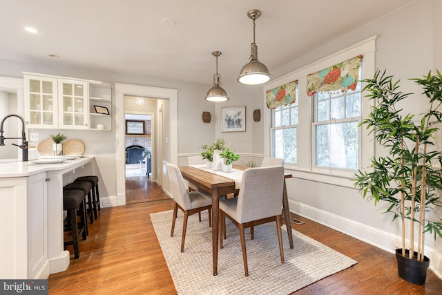 dining room with light wood-type flooring, visible vents, a fireplace, and baseboards