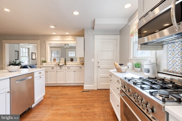 kitchen with light countertops, appliances with stainless steel finishes, light wood-style flooring, and white cabinetry