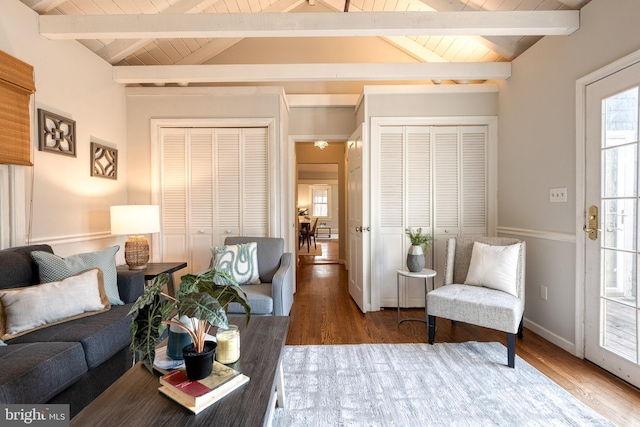 living area featuring vaulted ceiling with beams, wood finished floors, wood ceiling, and baseboards