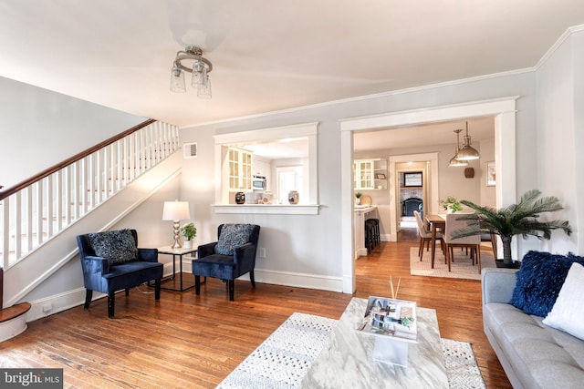 living area featuring baseboards, visible vents, stairway, wood finished floors, and a fireplace